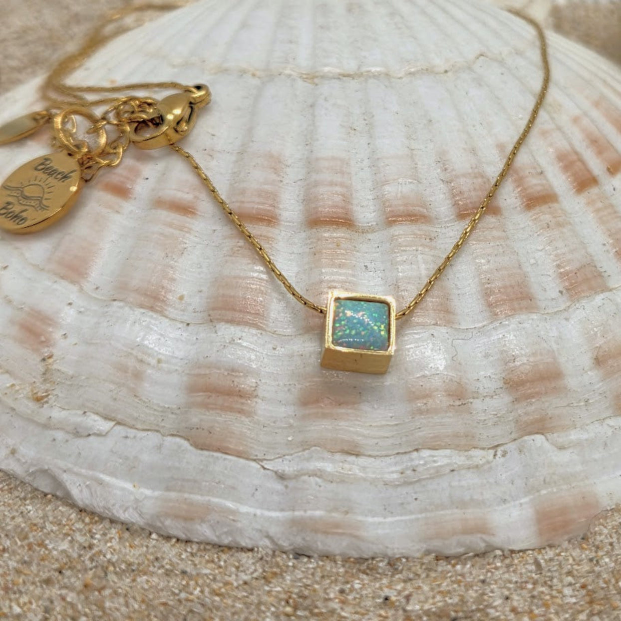 Gold necklace with a square pendant on a seashell