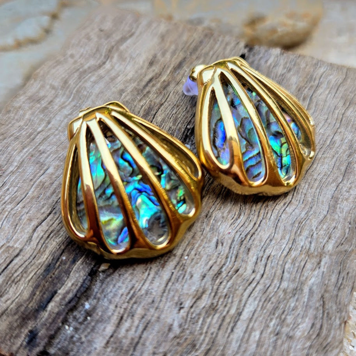 Gold earrings with colorful interior on a wooden surface