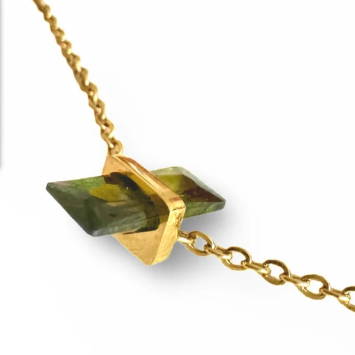 Gold necklace with a green stone pendant on a white background