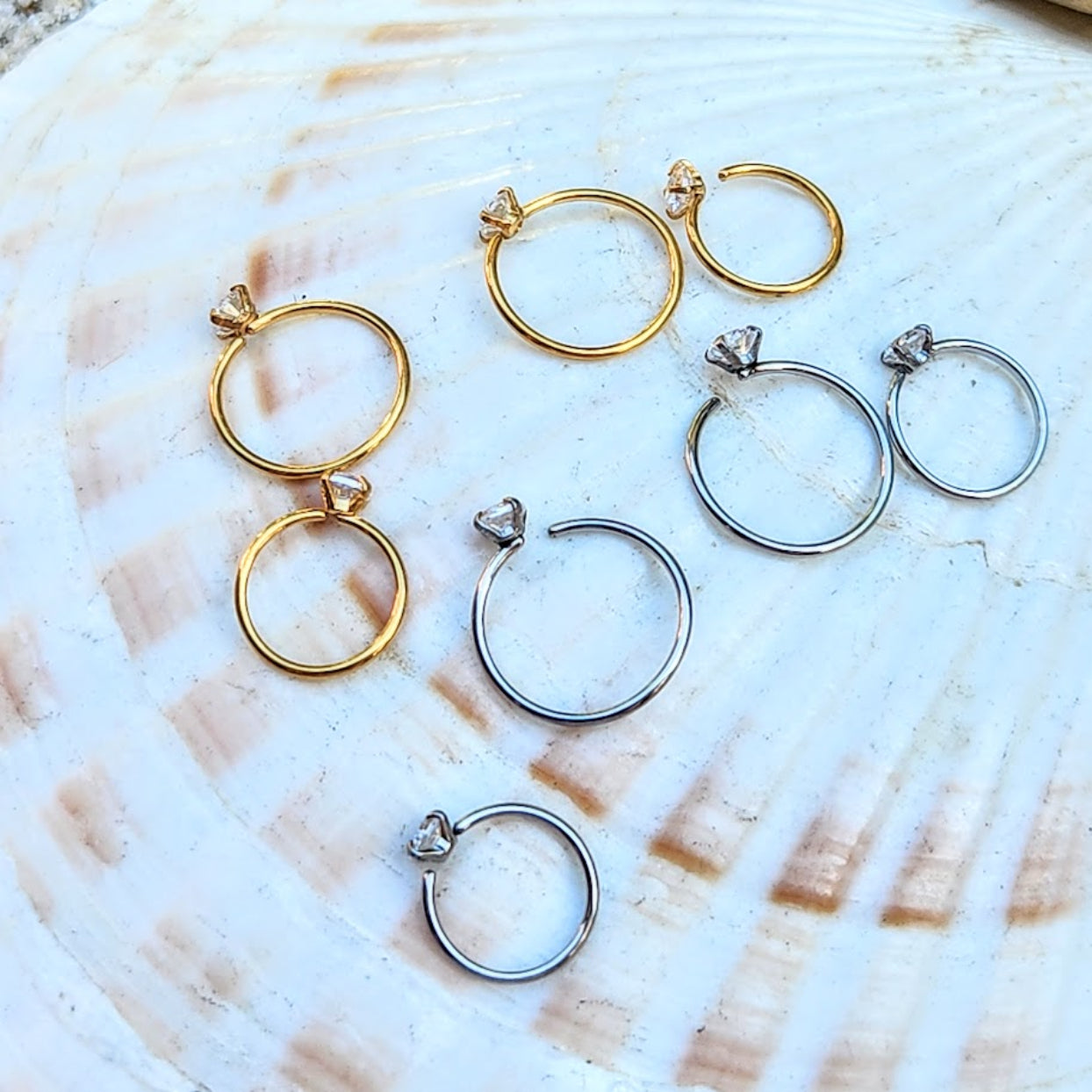 Gold and silver hoop earrings on a shell background