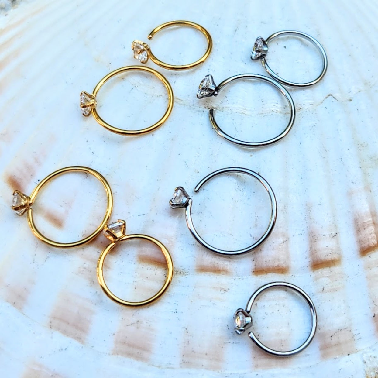 Gold and silver hoop earrings on a shell background