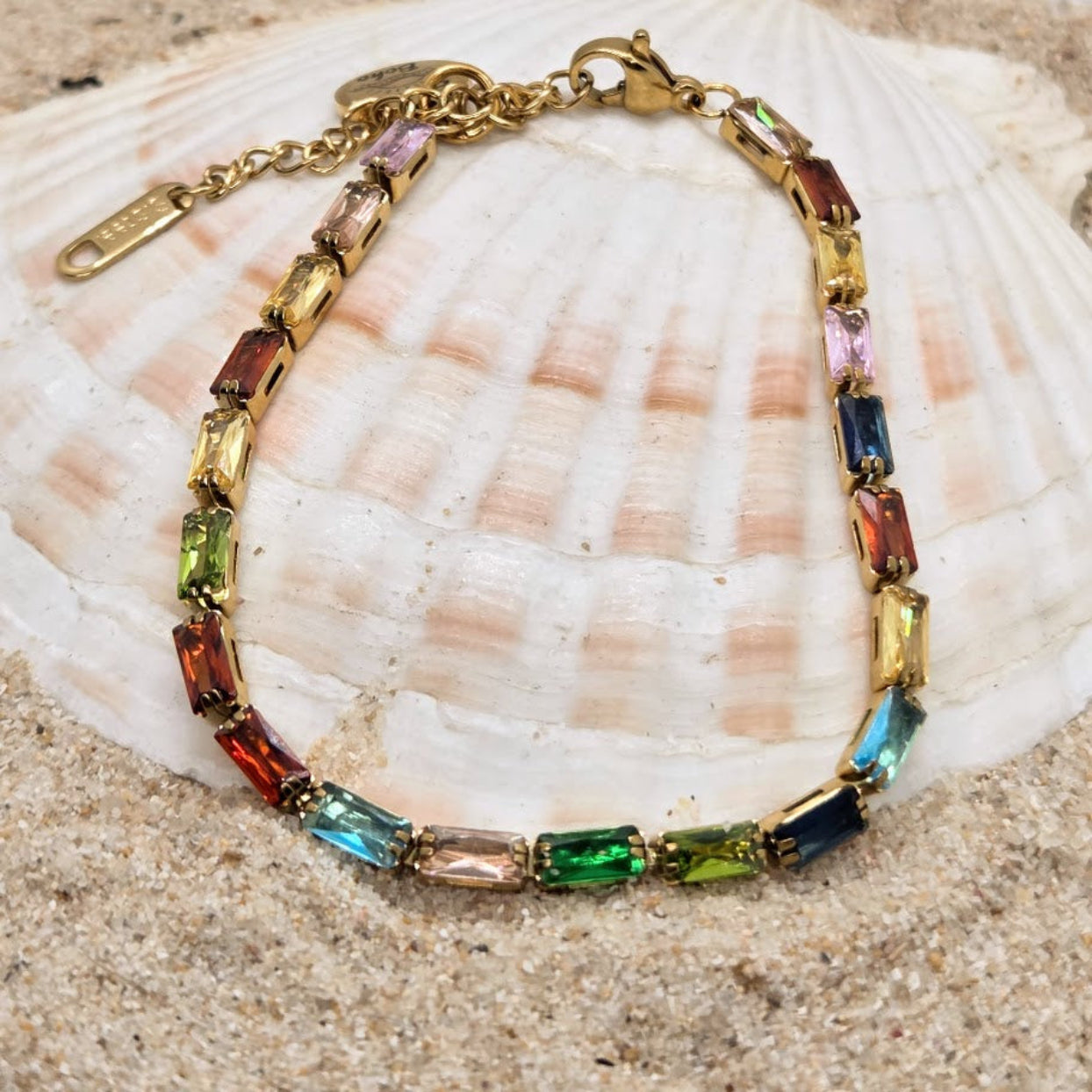 Multicolored gemstone bracelet on a shell with sand background