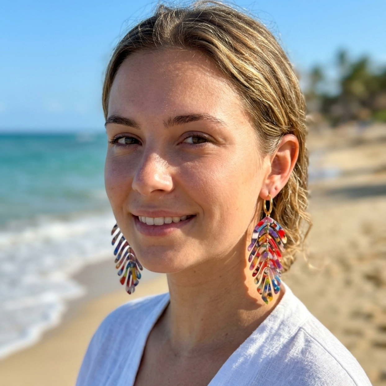 Woman on a beach wearing colorful earrings with a blurred background