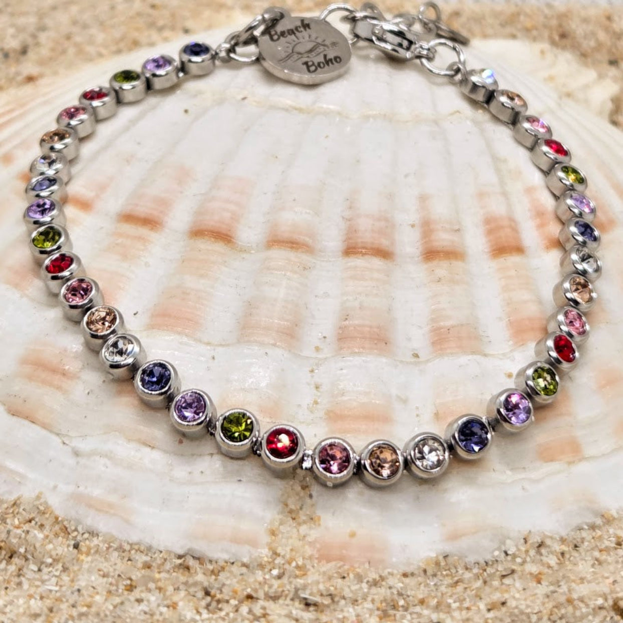 Multicolored beaded bracelet on a seashell with sand in the background
