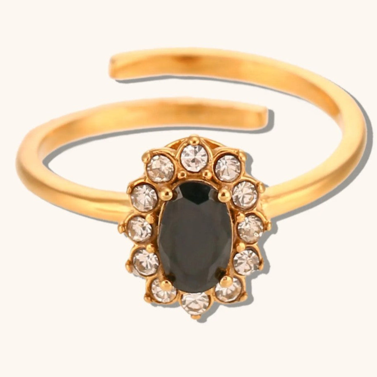 Gold open-toe ring with a central black gemstone and smaller clear stones on a white background