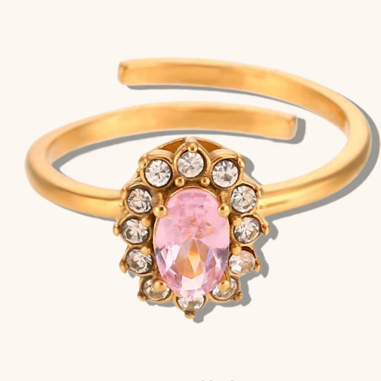 Gold bracelet with a pink gemstone and clear stones on a white background