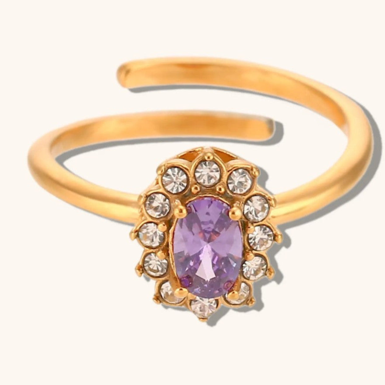 Gold ring with a purple gemstone and clear stones on a white background