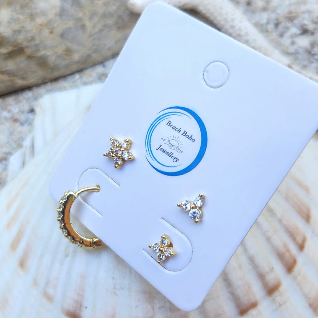 Gold jewelry set on a branded card with a shell background