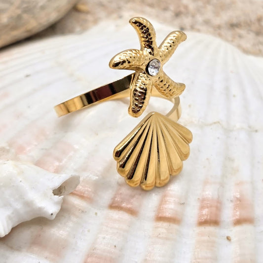 Gold ring with starfish and shell design on a seashell background