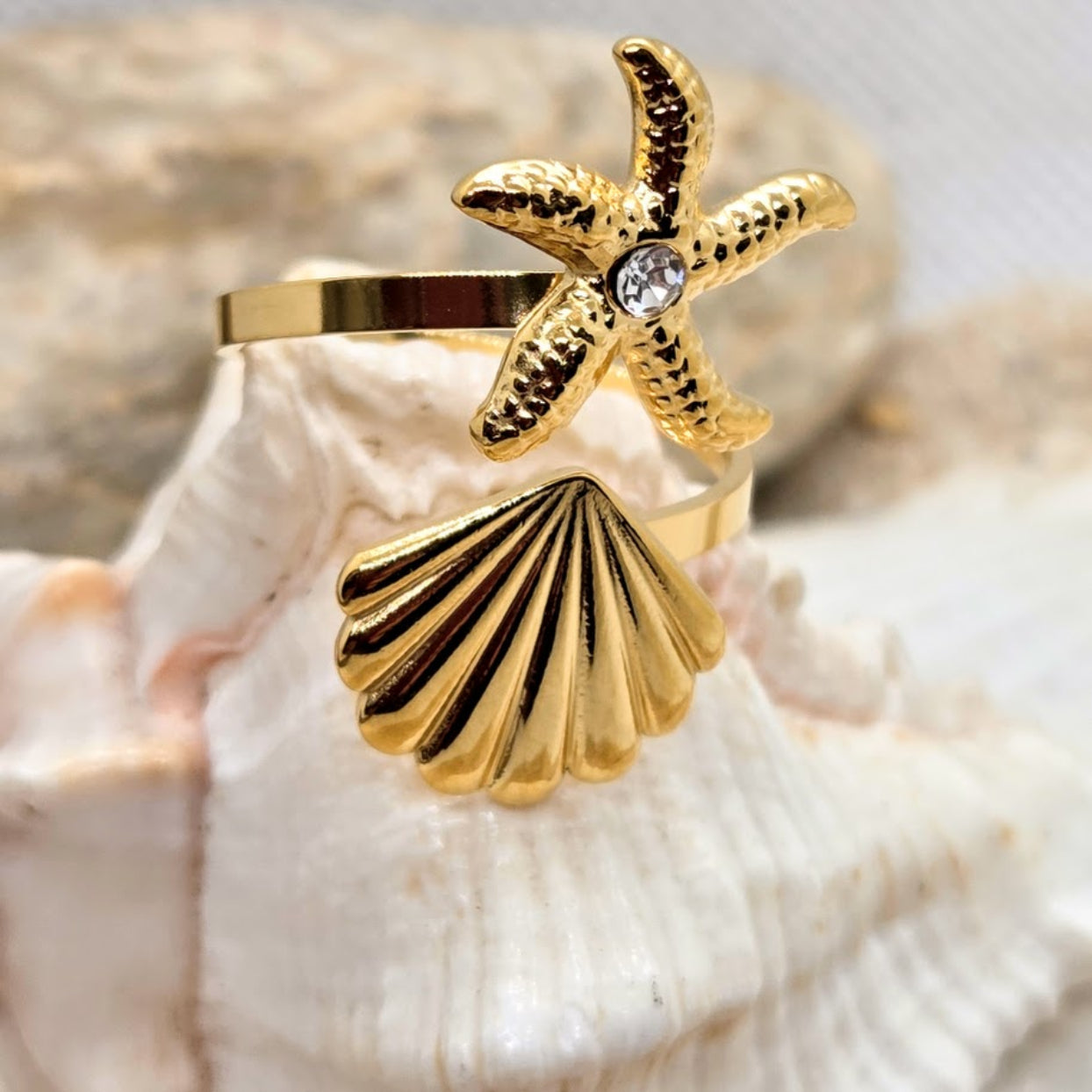 Gold ring with starfish and shell design on a shell background