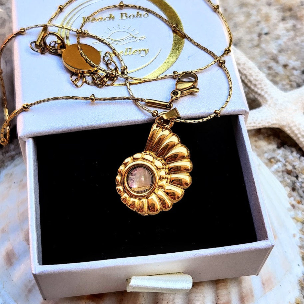 Gold necklace with a pendant in a jewelry box on a textured surface