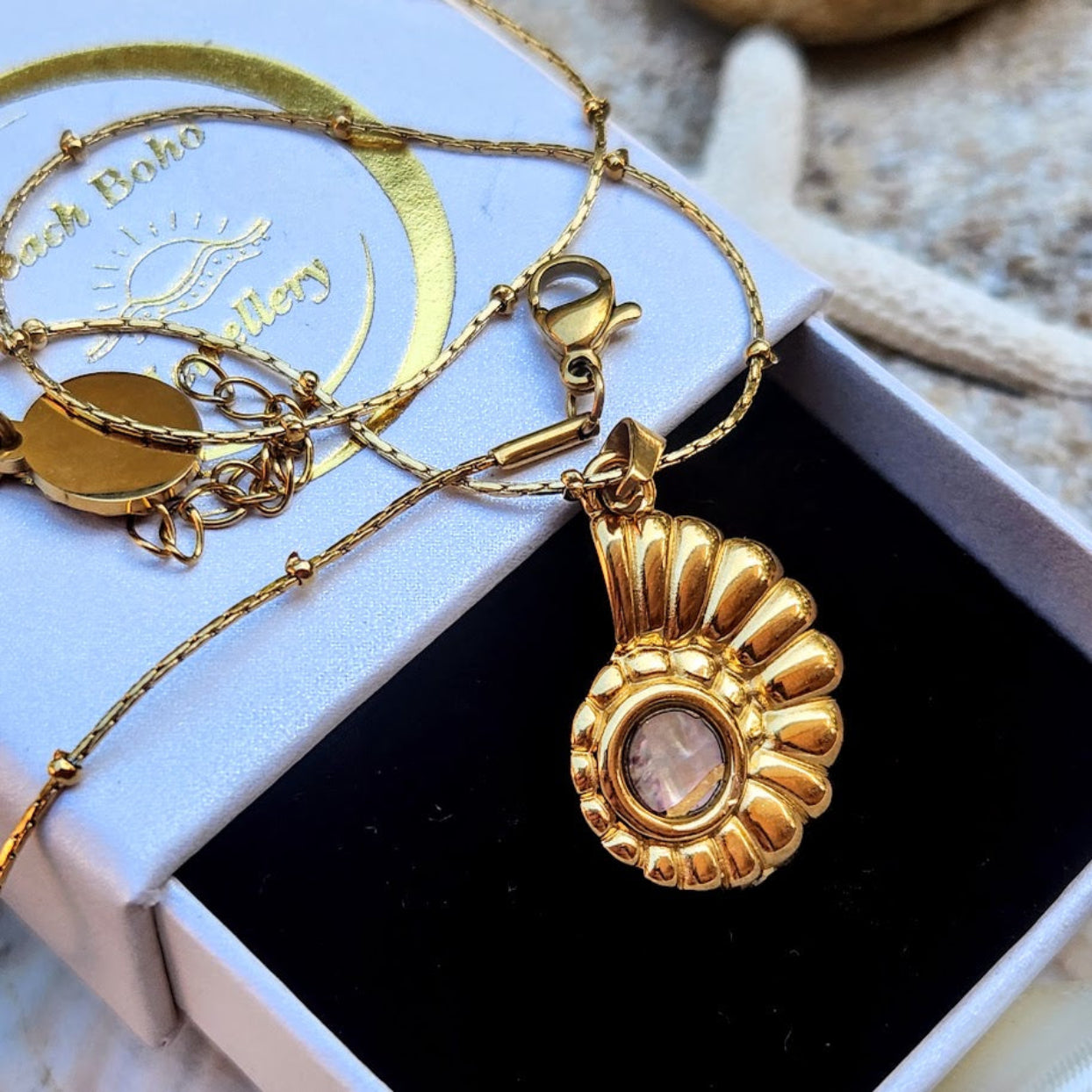 Gold necklace with a pendant in a box, featuring 'Boho' branding.