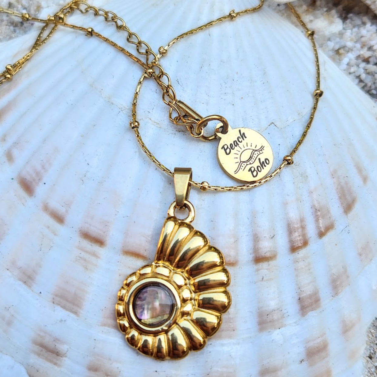 Gold necklace with a decorative pendant on a shell background