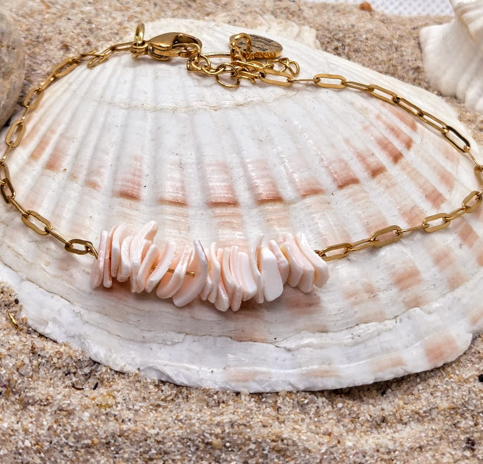 Bracelet with shell beads on a seashell against a sandy background