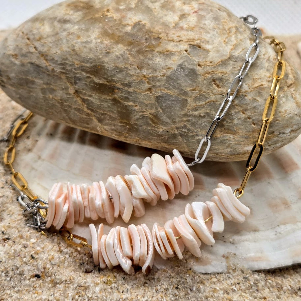 Necklace with shell beads and gold chain on a stone surface