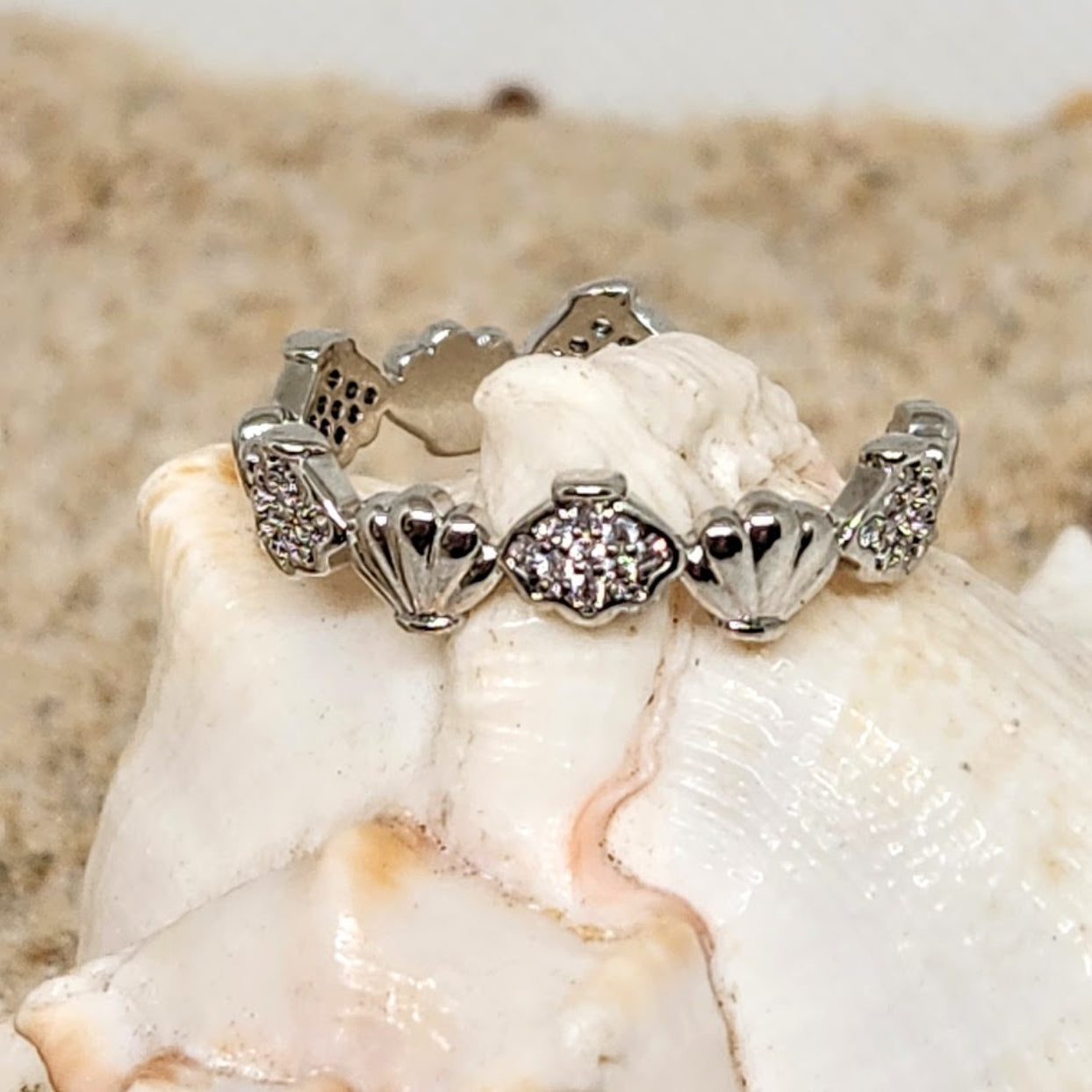 Silver bracelet with heart and shell designs on a seashell