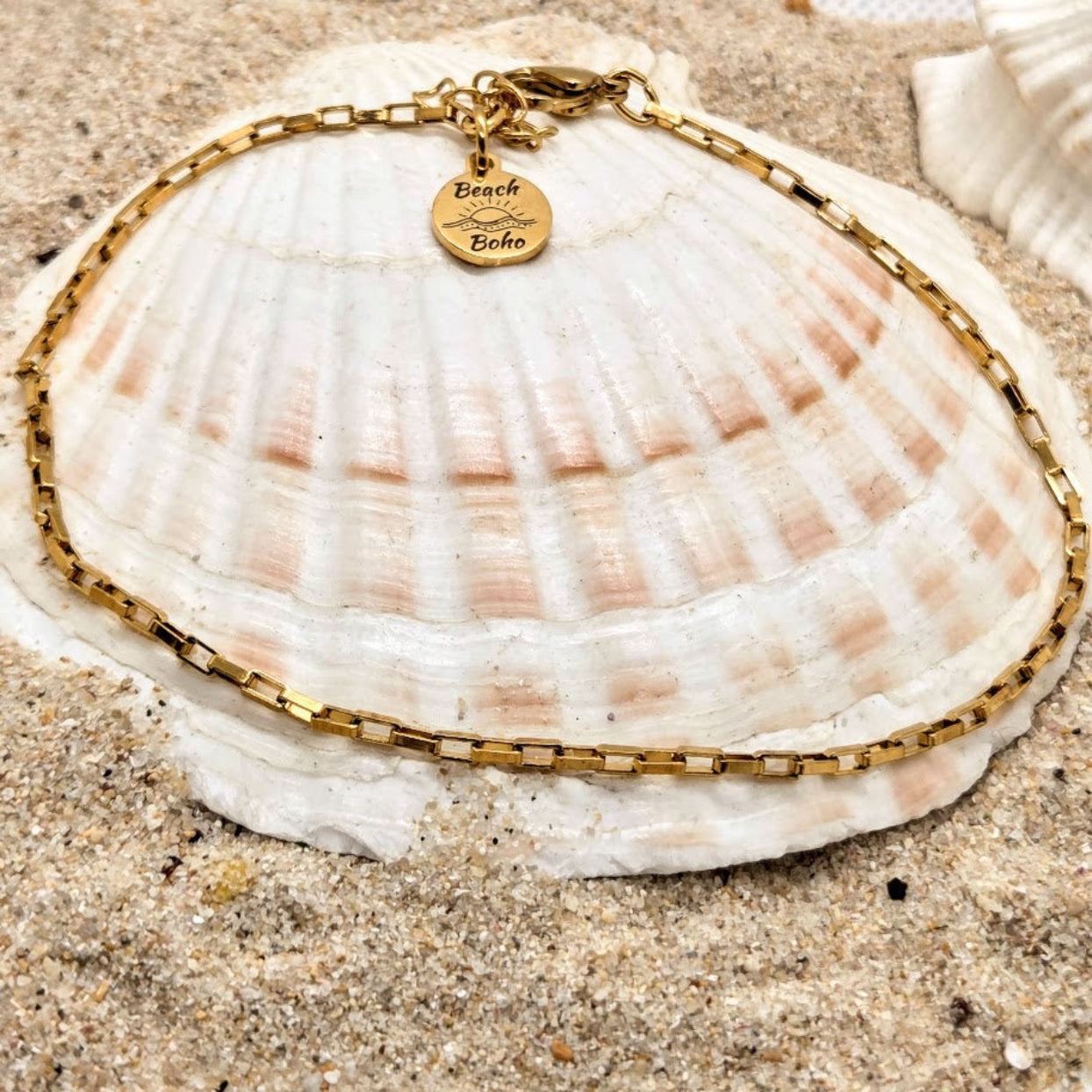 Gold bracelet with a heart-shaped tag on a seashell