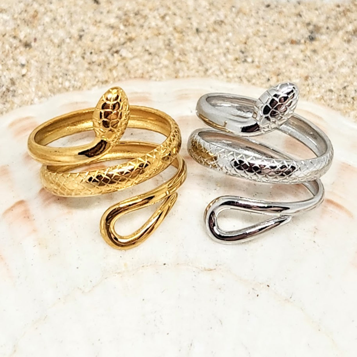 Gold and silver snake-shaped rings on a textured surface