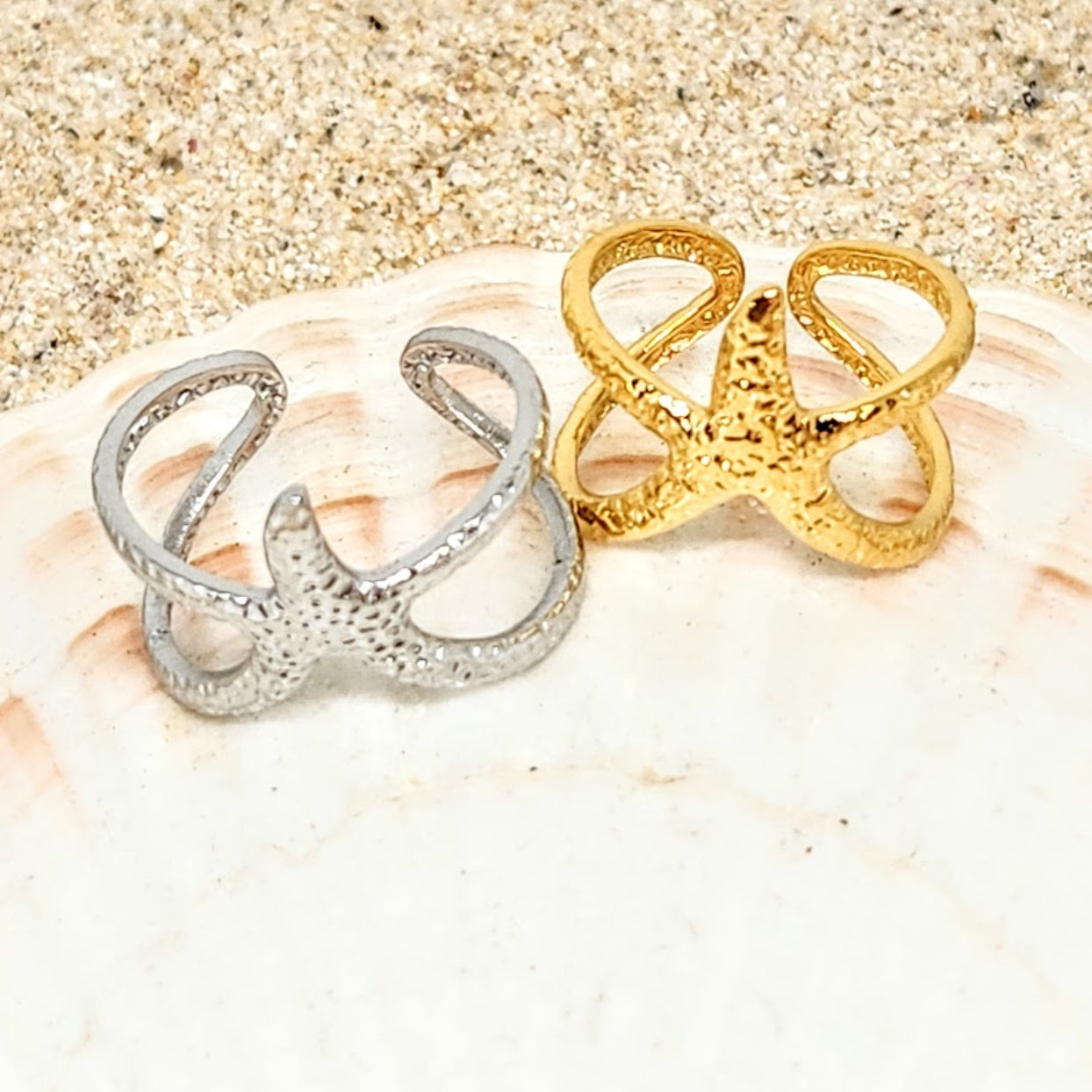 Gold and silver rings on a shell with sand background