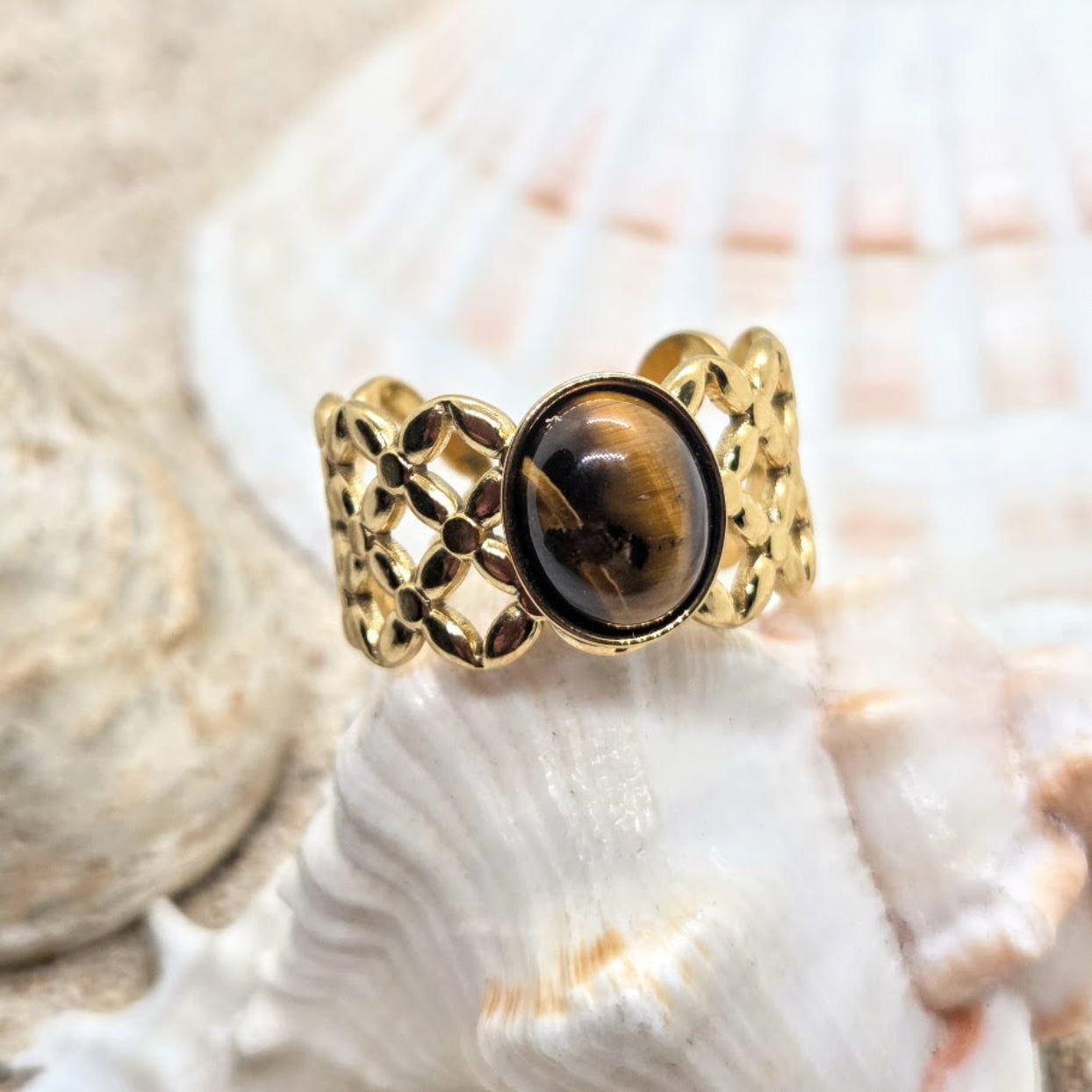 Gold ring with a brown gemstone on a shell background