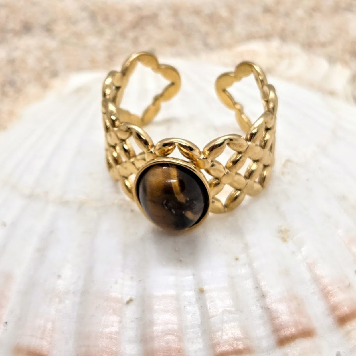 Gold ring with a brown gemstone on a seashell