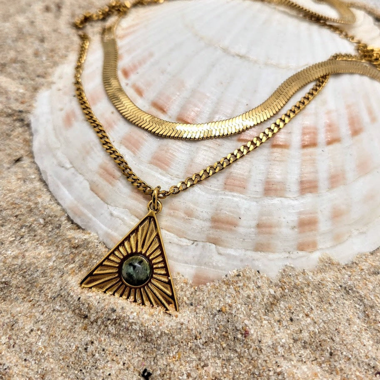 Gold necklace with a triangular pendant on a seashell