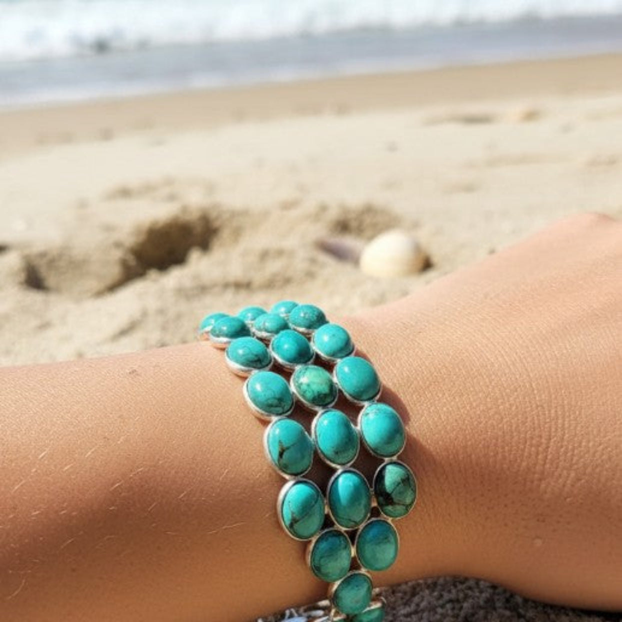 Turquoise bracelet on a wrist with a beach background