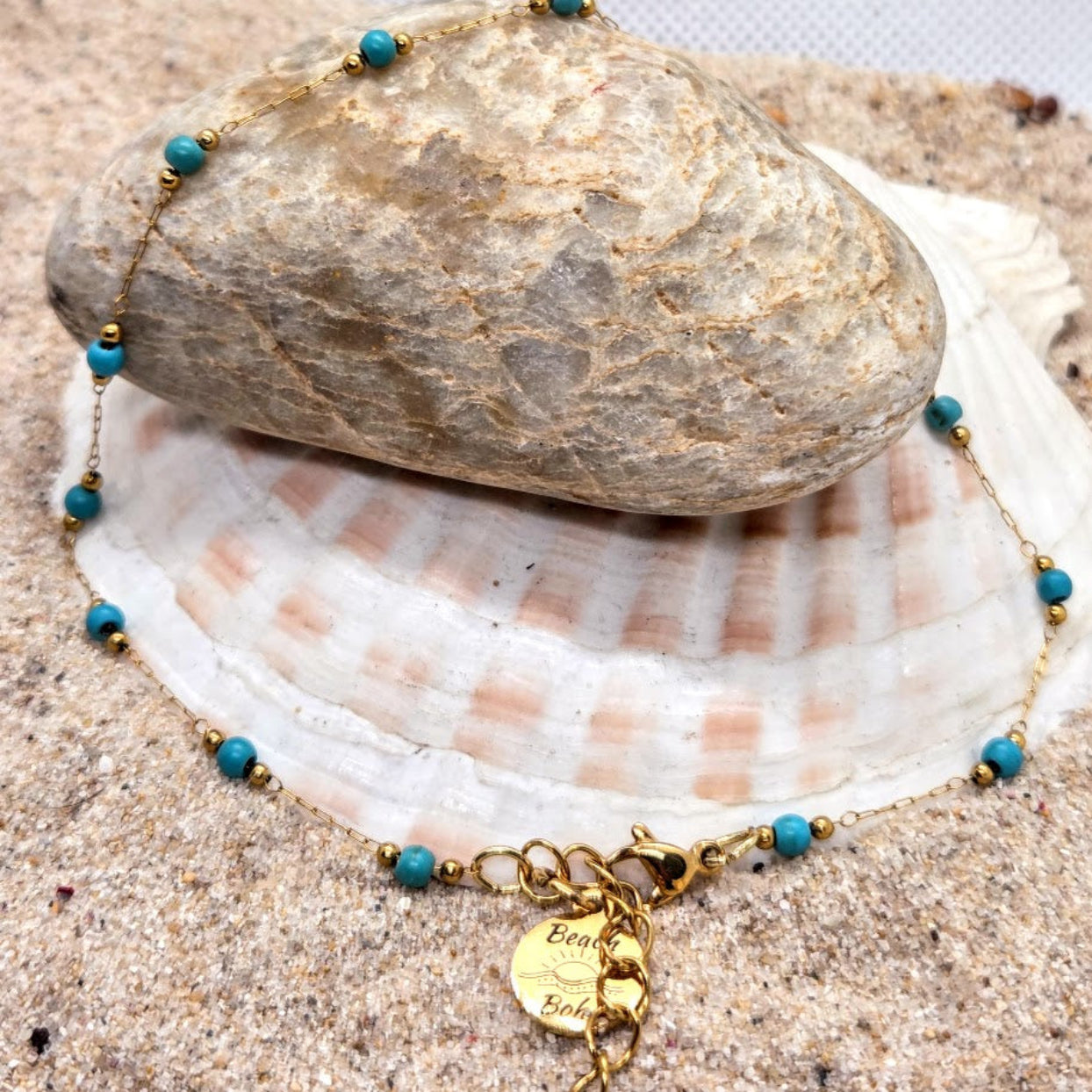 Gold anklet with blue beads on a shell and rock