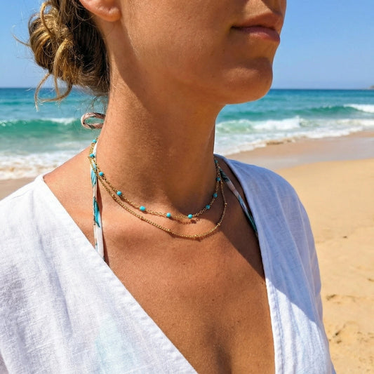 Woman on a beach wearing layered necklaces with ocean view