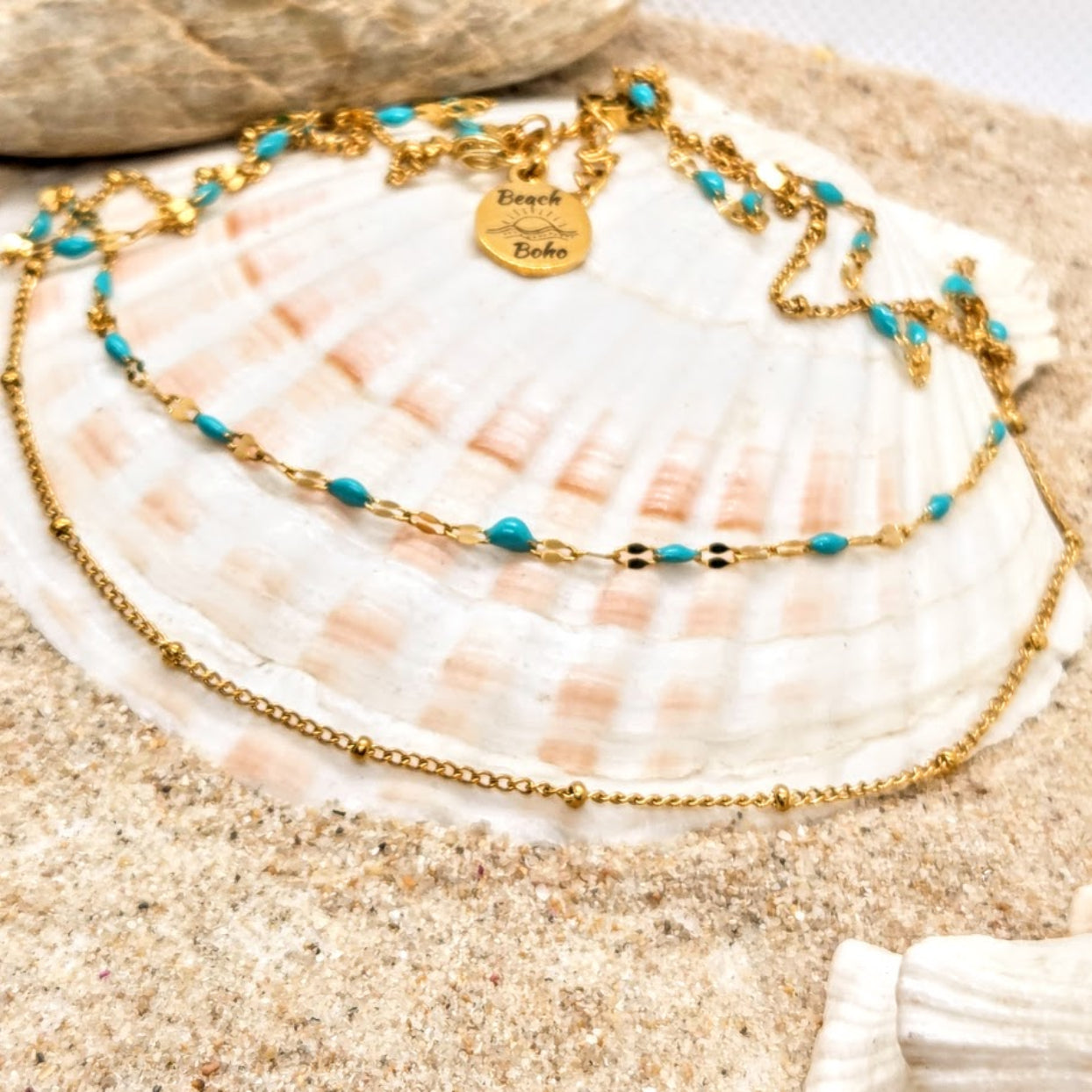 Gold and turquoise beaded necklace on a seashell with sand background