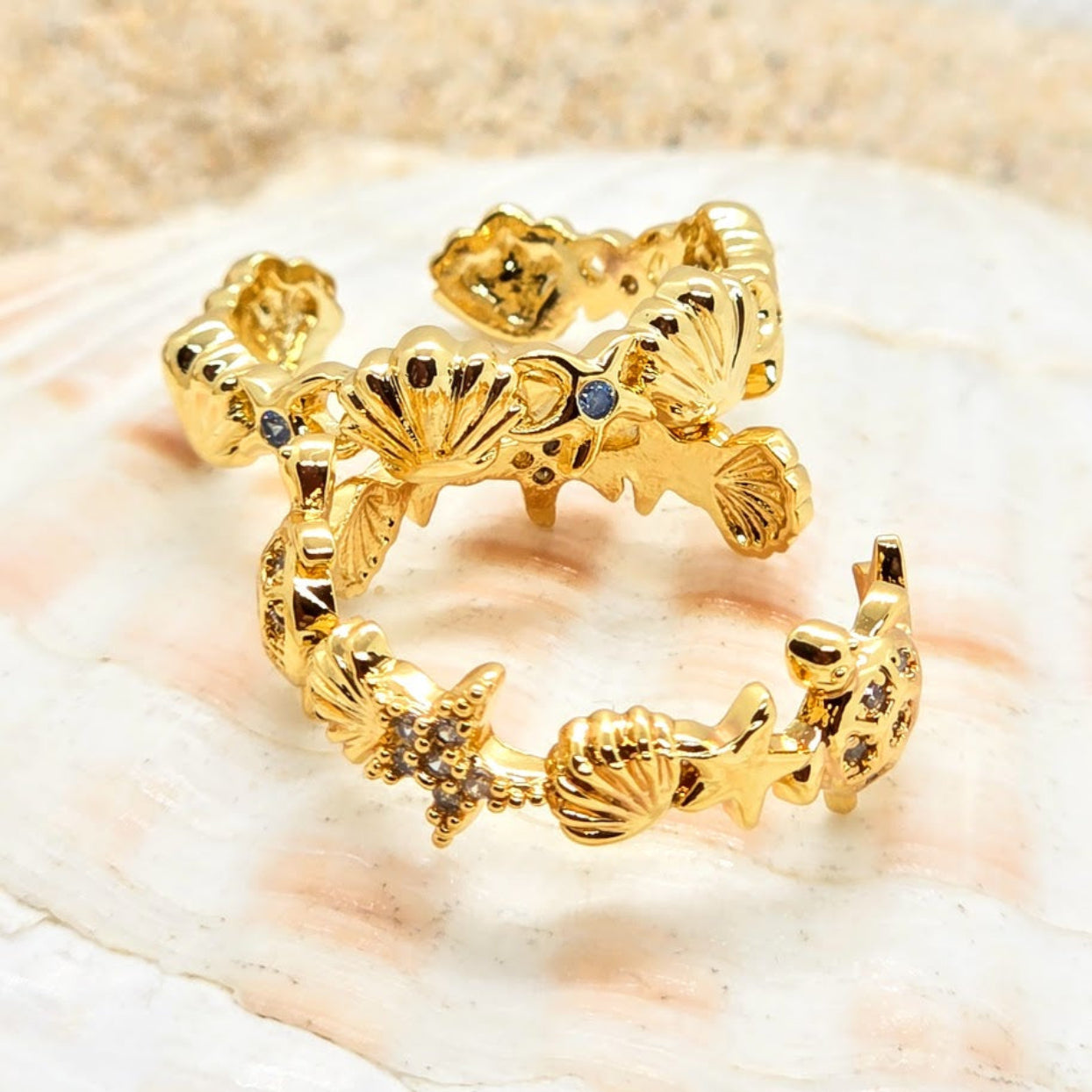 Gold ring with shell designs on a beige background