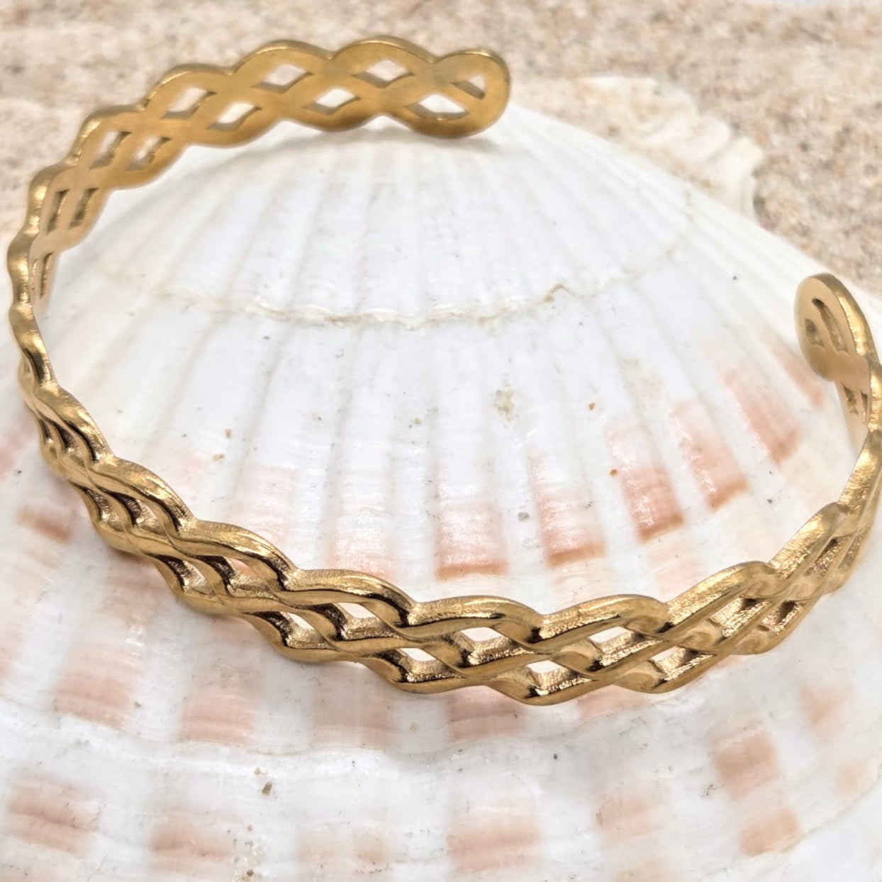 Gold braided bracelet on a seashell