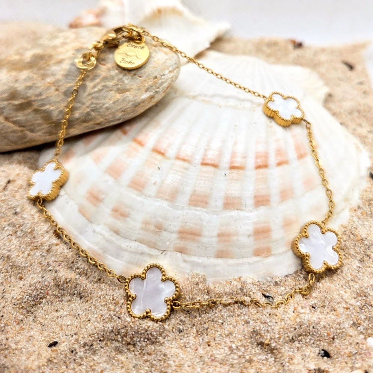 Gold bracelet with floral designs on a seashell in sand